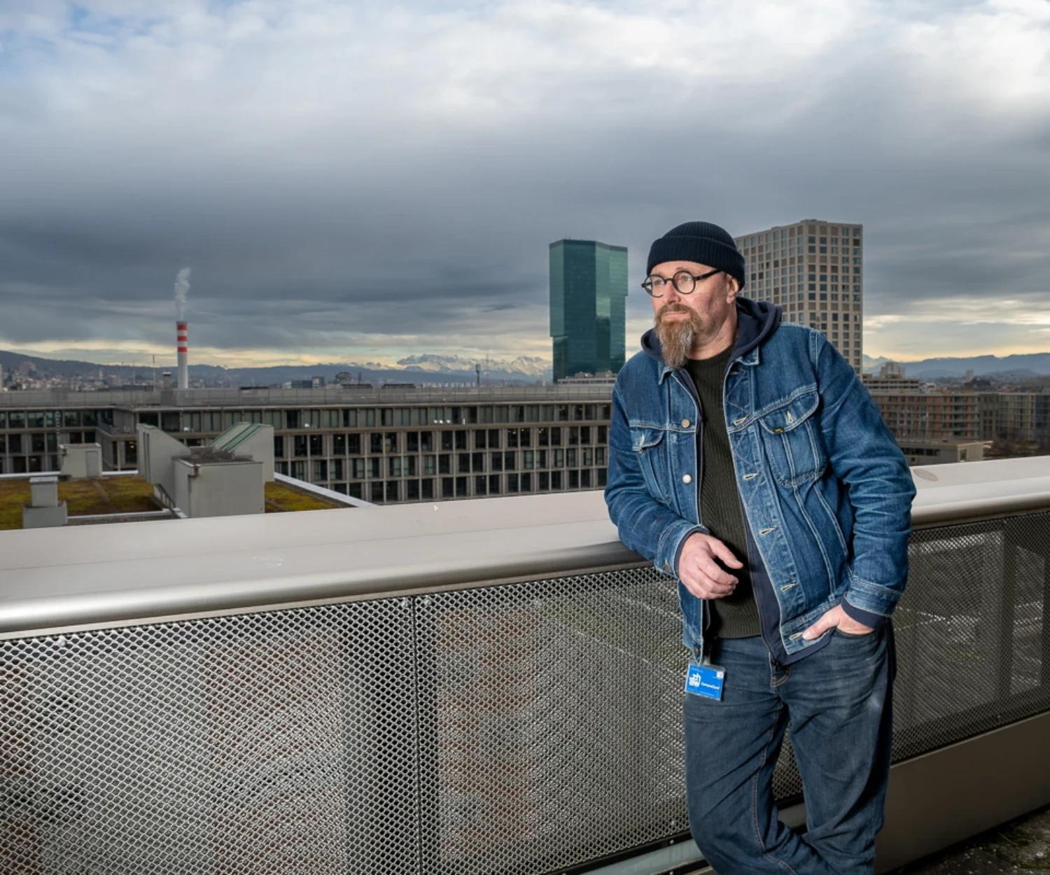 Editorialbild. Mann lehnt auf einer Dachterrasse mit Blick über Zürich.
