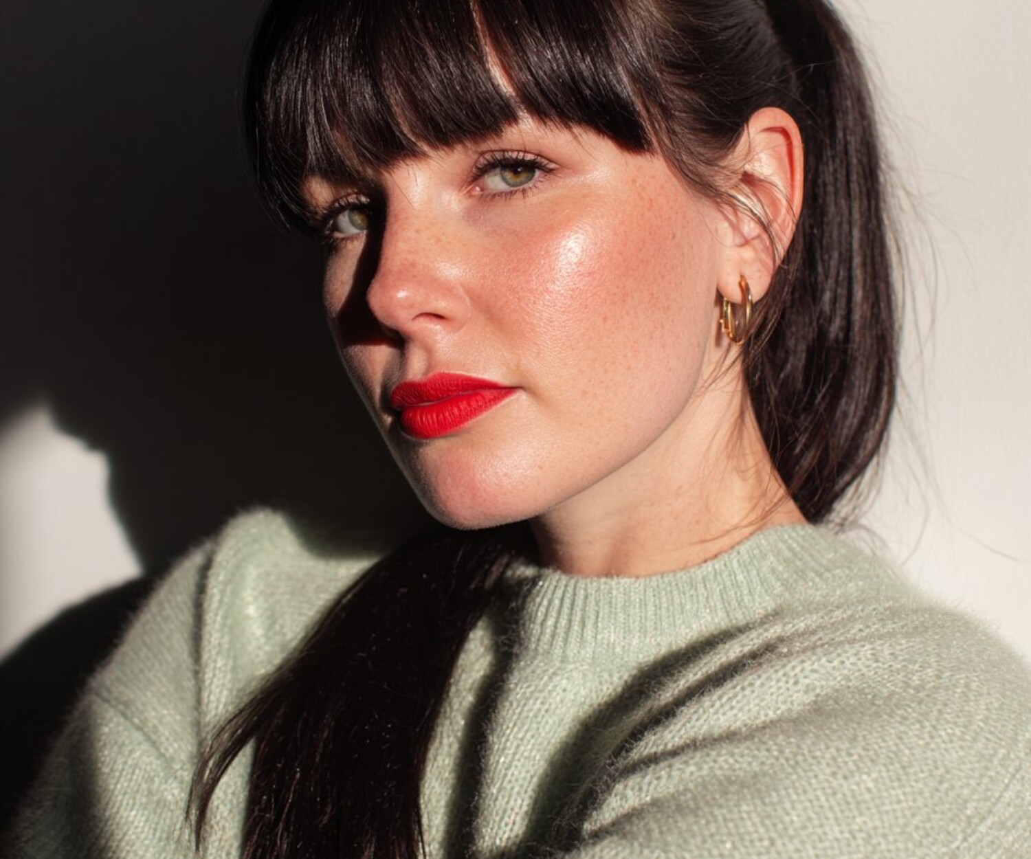 Portrait einer schönen Frau in hell salbeifarbenem Pullover und langen braunen Haaren und Fransen