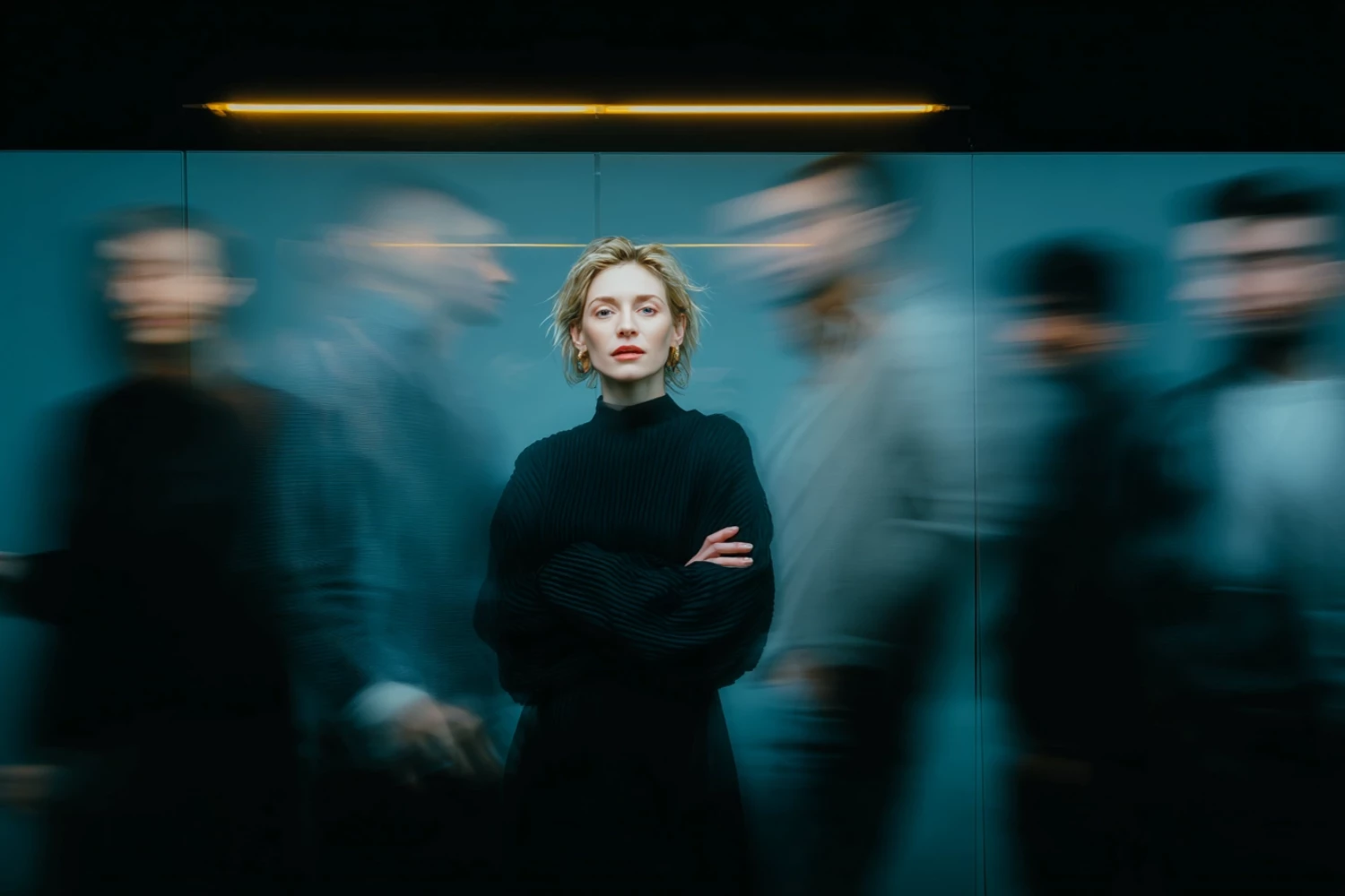 Person in moderner Büroumgebung steht ruhig im Fokus, während das Team dynamisch im Hintergrund vorbeigeht – Symbolbild für KI‑Firmentraining für Marketingteams.